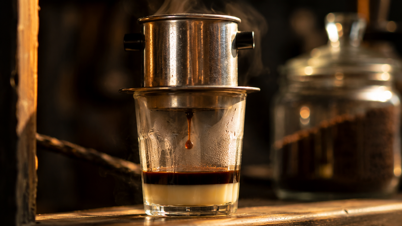 Vietnamese phin filter dripping coffee into a glass over sweetened condensed milk
